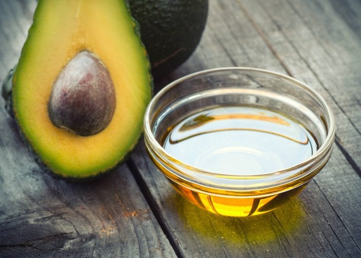avocado and bowl with oil on a wooden table