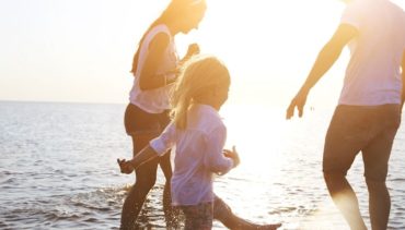 dad with mom and daughter playing by the sea