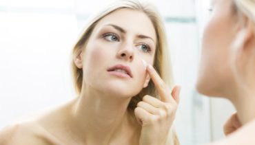 woman applies cream on her face