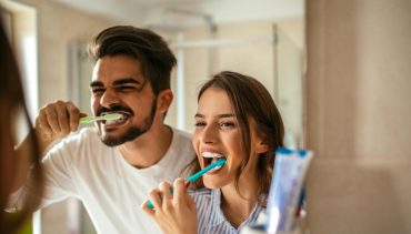 couple washing their teeth in fron of mirror